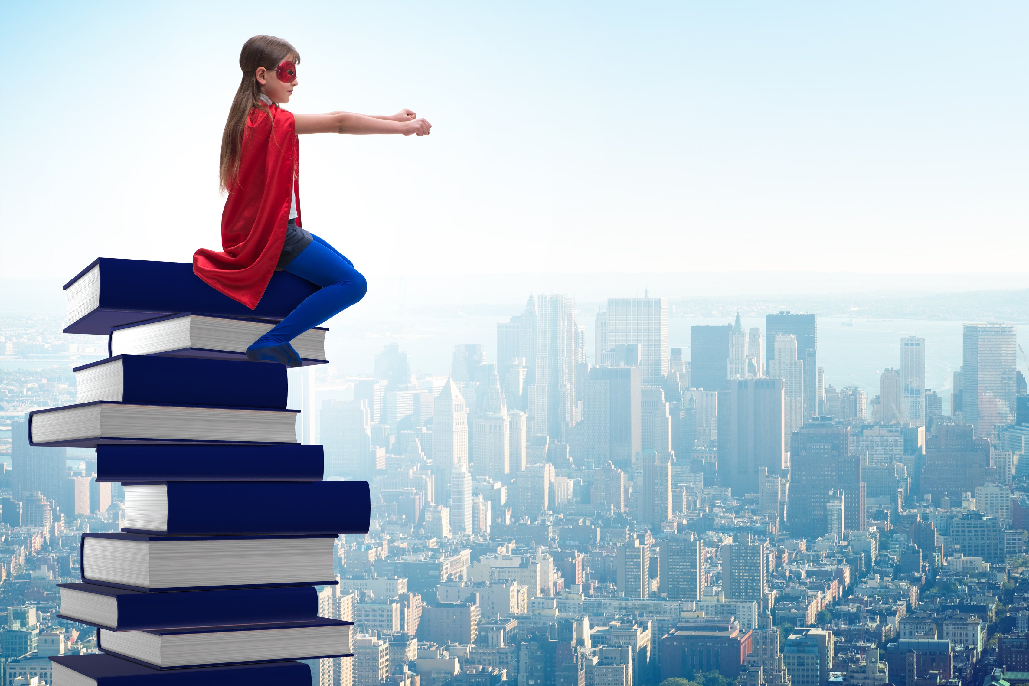 Superhero Little Girl Sitting on a Pile of Books